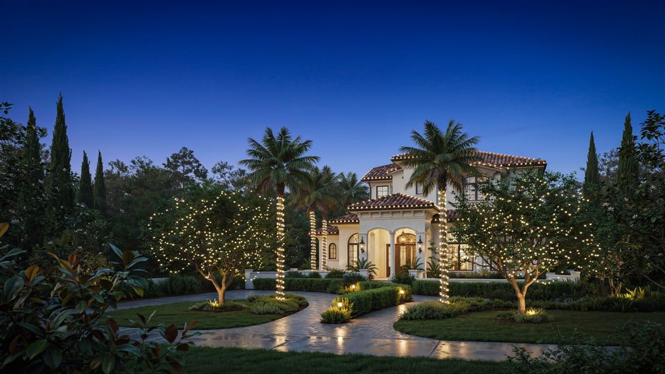 Estate at blue hour with twinkle lights on the trees and wrapped palm trunks